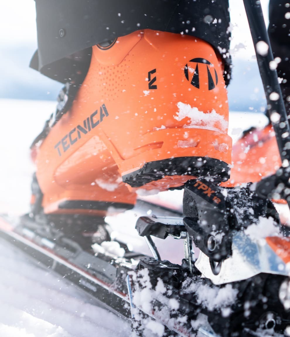 Closeup of ski boot stepping into ski binding on snow.