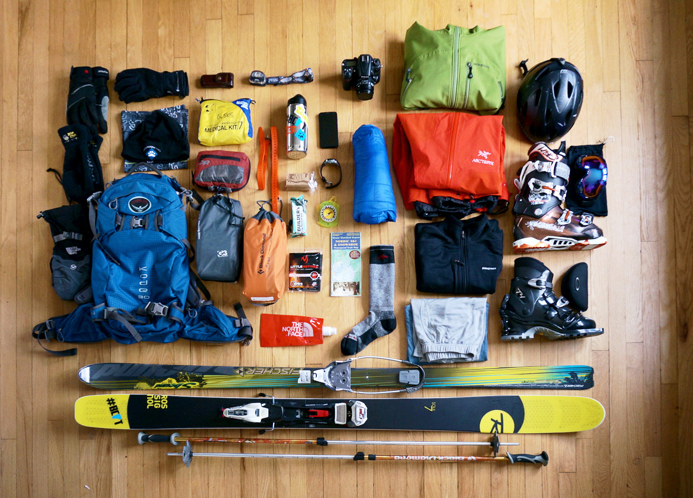 Family packing ski gear for a trip inside a lodge, including boots, jackets, helmets, and winter clothing